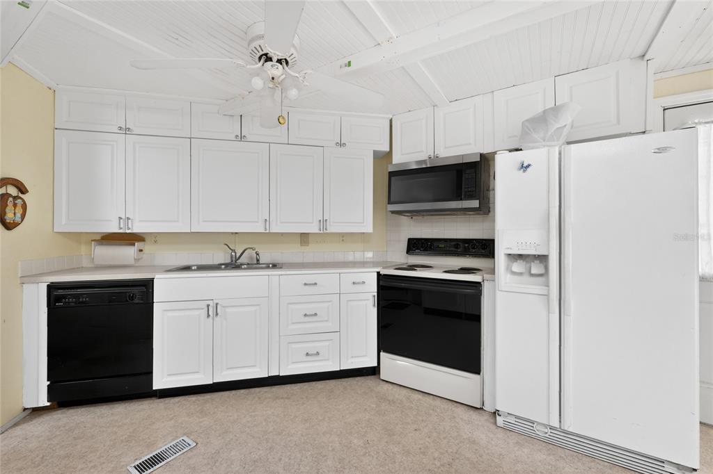 A kitchen features white cabinets, a black dishwasher, a black stove, and a white refrigerator — 1380 SEAGULL DRIVE, ENGLEWOOD, FL