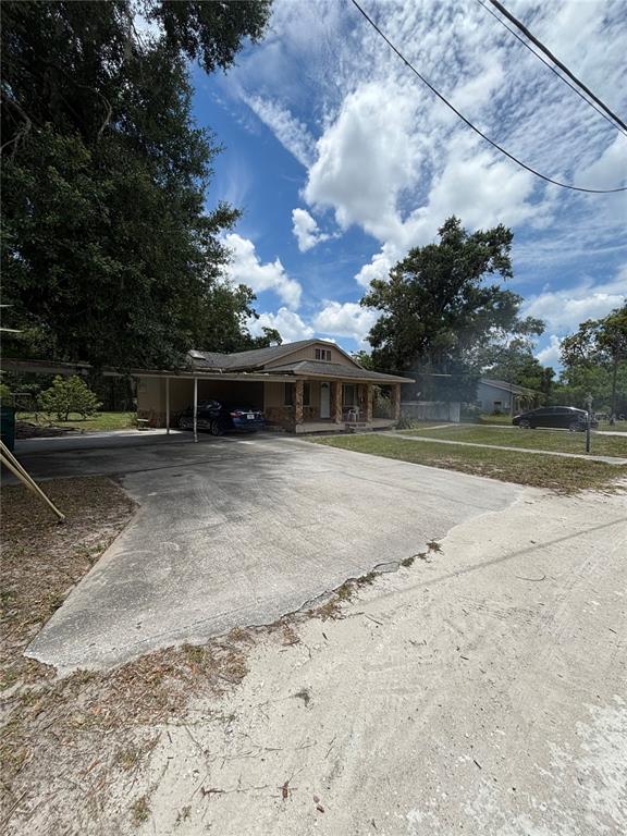 A single-story house with a carport and a large concrete driveway under a cloudy sky — 13232 BLISSFIELD ROAD, ODESSA, FL