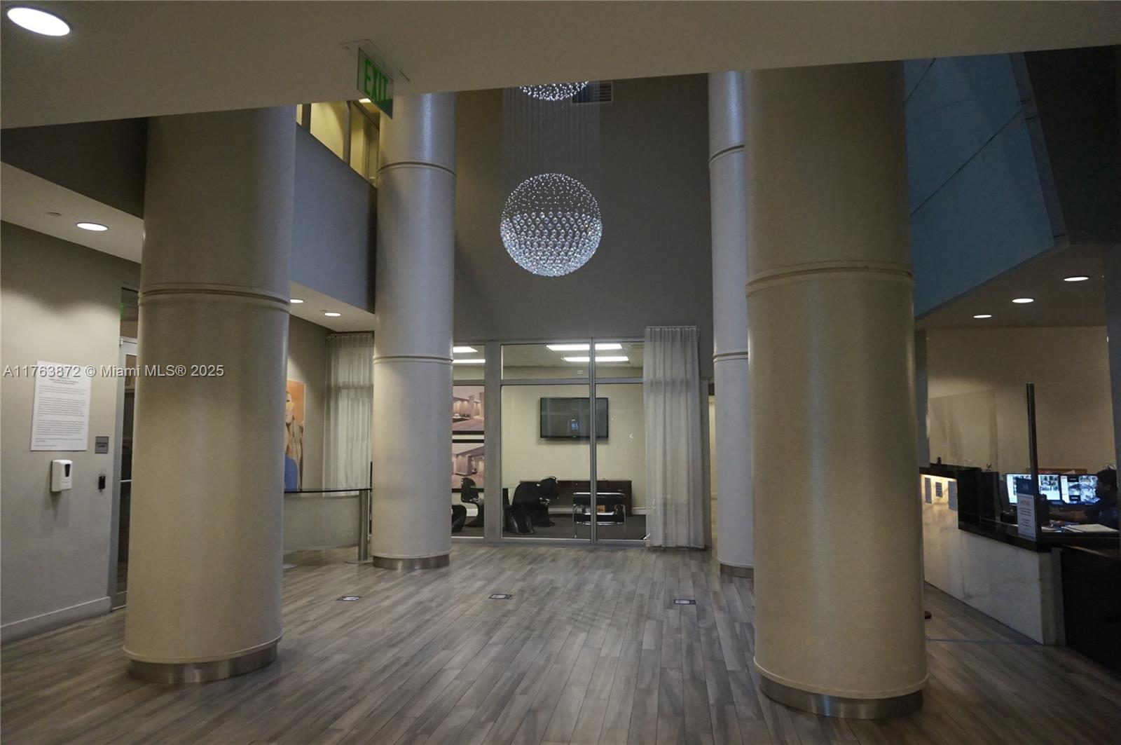 A spacious lobby features large cylindrical columns, wood-look flooring, and a modern spherical chandelier — 1750 N Bayshore Dr # 2215, Miami FL 33132, MIAMI, FL
