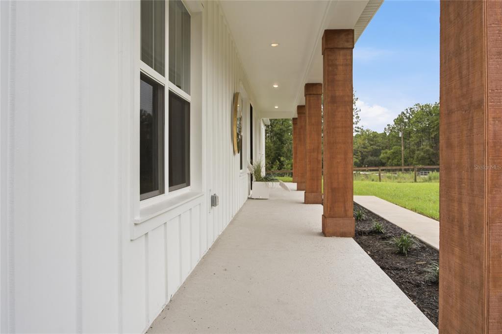 A covered porch features white board-and-batten siding, recessed lighting, and wooden support columns — 7539 SW 129TH TERRACE ROAD, DUNNELLON, FL