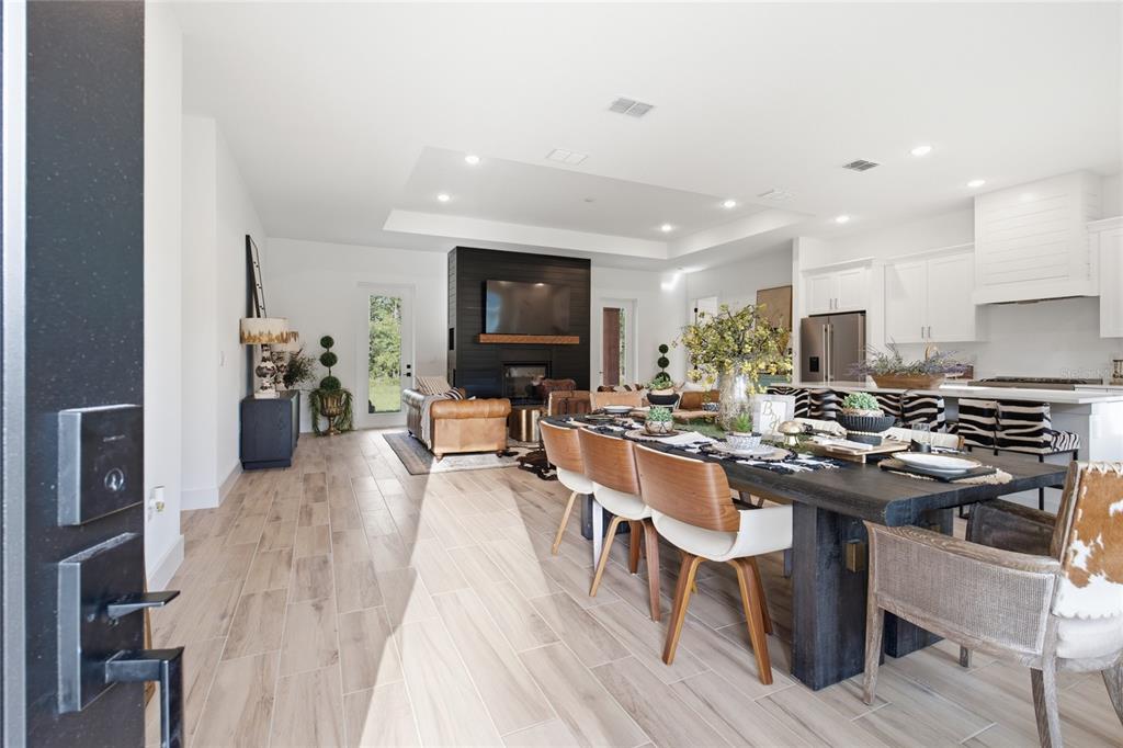 An open-concept living and dining area features a black fireplace, wood floors, and white cabinetry — 7539 SW 129TH TERRACE ROAD, DUNNELLON, FL