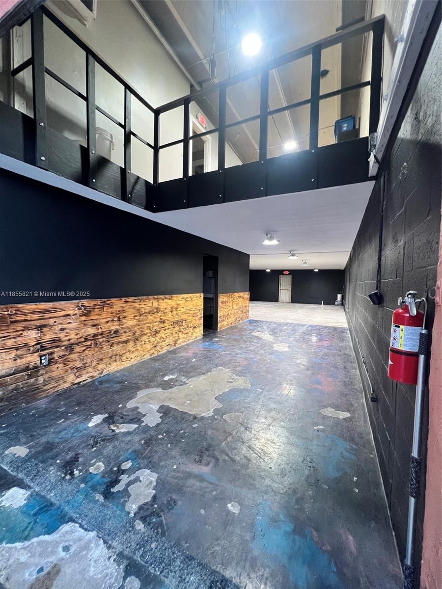 An industrial space features a black-painted mezzanine, wood-paneled walls, and a worn concrete floor — 1657 W 40th St # 6, Hialeah FL 33012, HIALEAH, FL