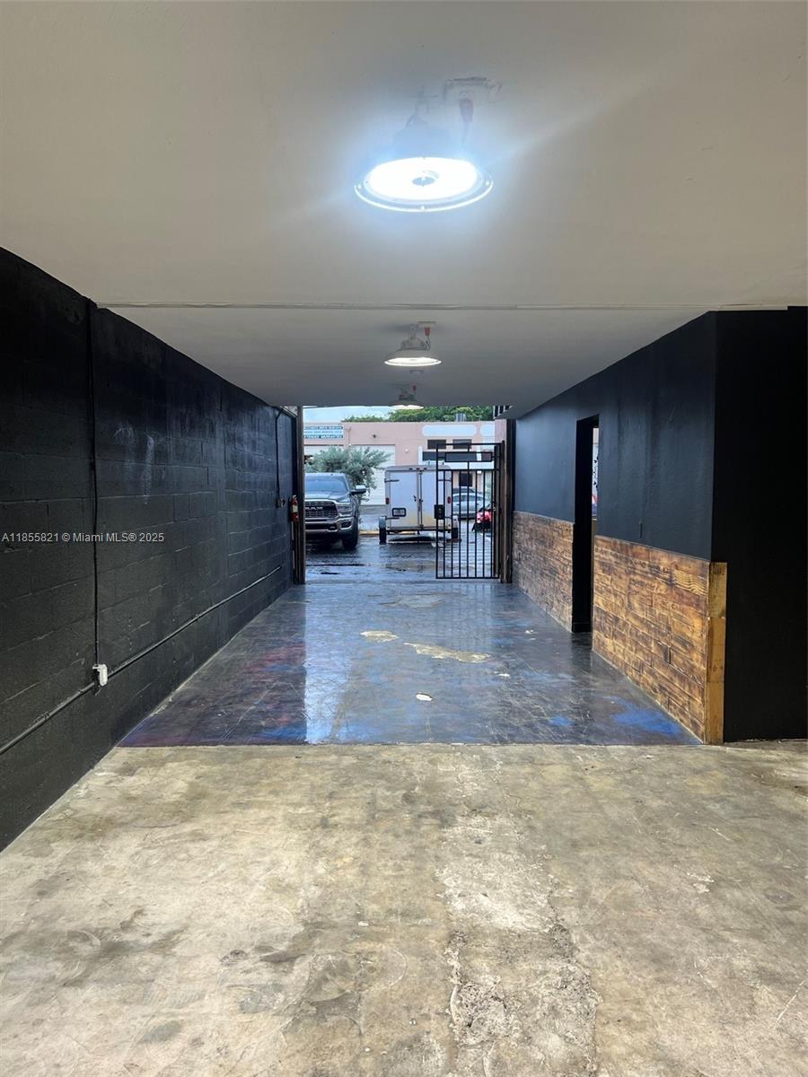 A covered outdoor space features black painted walls, wood paneling, and a stained concrete floor — 1657 W 40th St # 6, Hialeah FL 33012, HIALEAH, FL