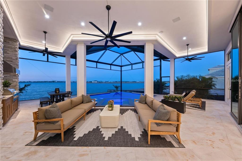 A covered outdoor patio features two sofas, a pool, and a view of the water — 800 BLUE SHELL LOOP, SARASOTA, FL