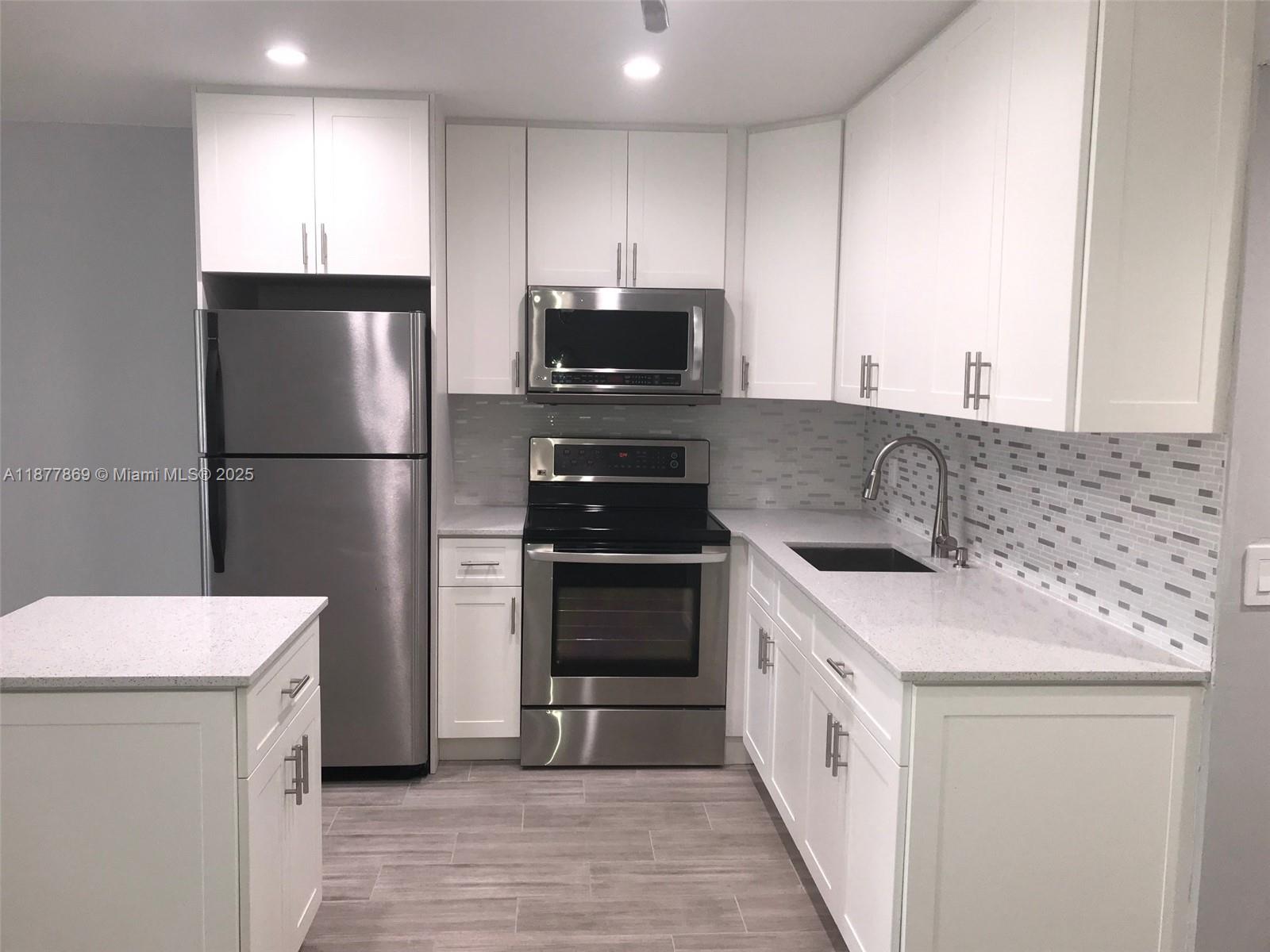 A kitchen features white cabinets, stainless steel appliances, quartz countertops, and a tiled backsplash — 17 Keswick A # 17, Deerfield Beach FL 33442, DEERFIELD BEACH, FL