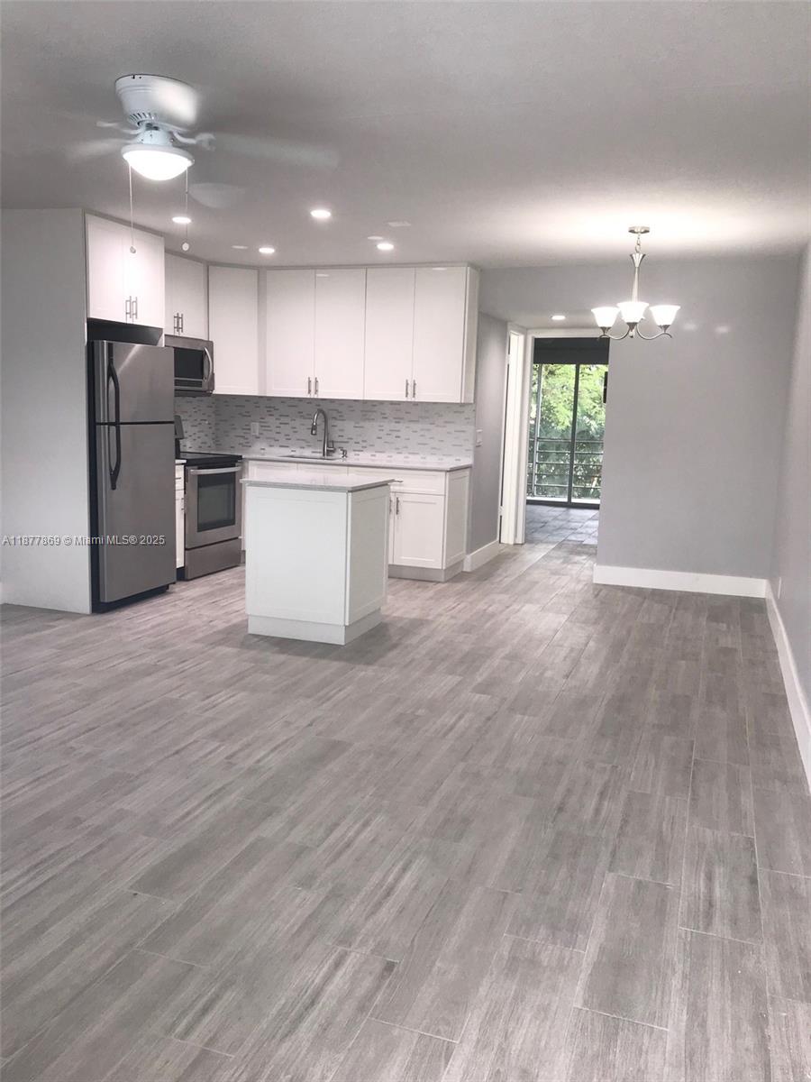 A kitchen with white cabinets, stainless steel appliances, and gray wood-look tile flooring — 17 Keswick A # 17, Deerfield Beach FL 33442, DEERFIELD BEACH, FL