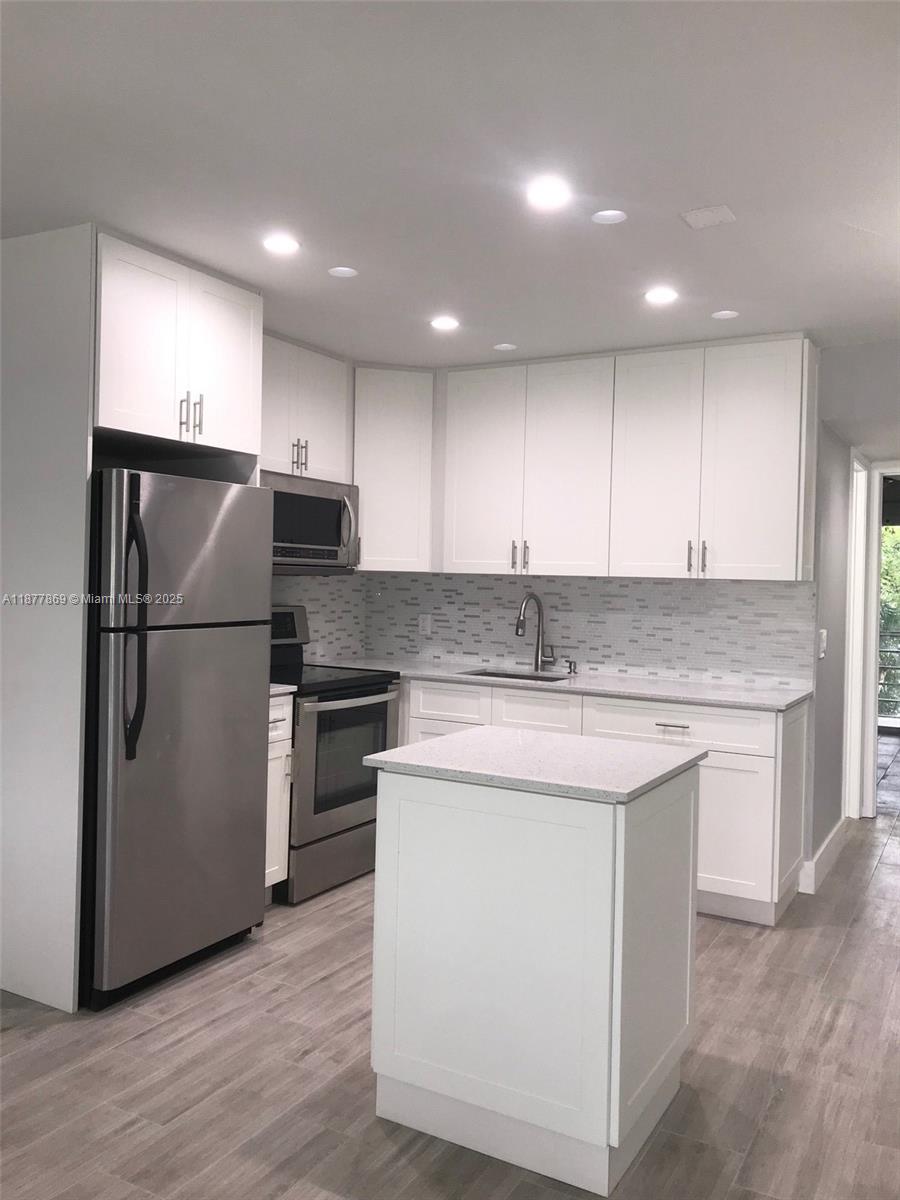 A kitchen features white cabinets, stainless steel appliances, a small island, and light-colored flooring — 17 Keswick A # 17, Deerfield Beach FL 33442, DEERFIELD BEACH, FL