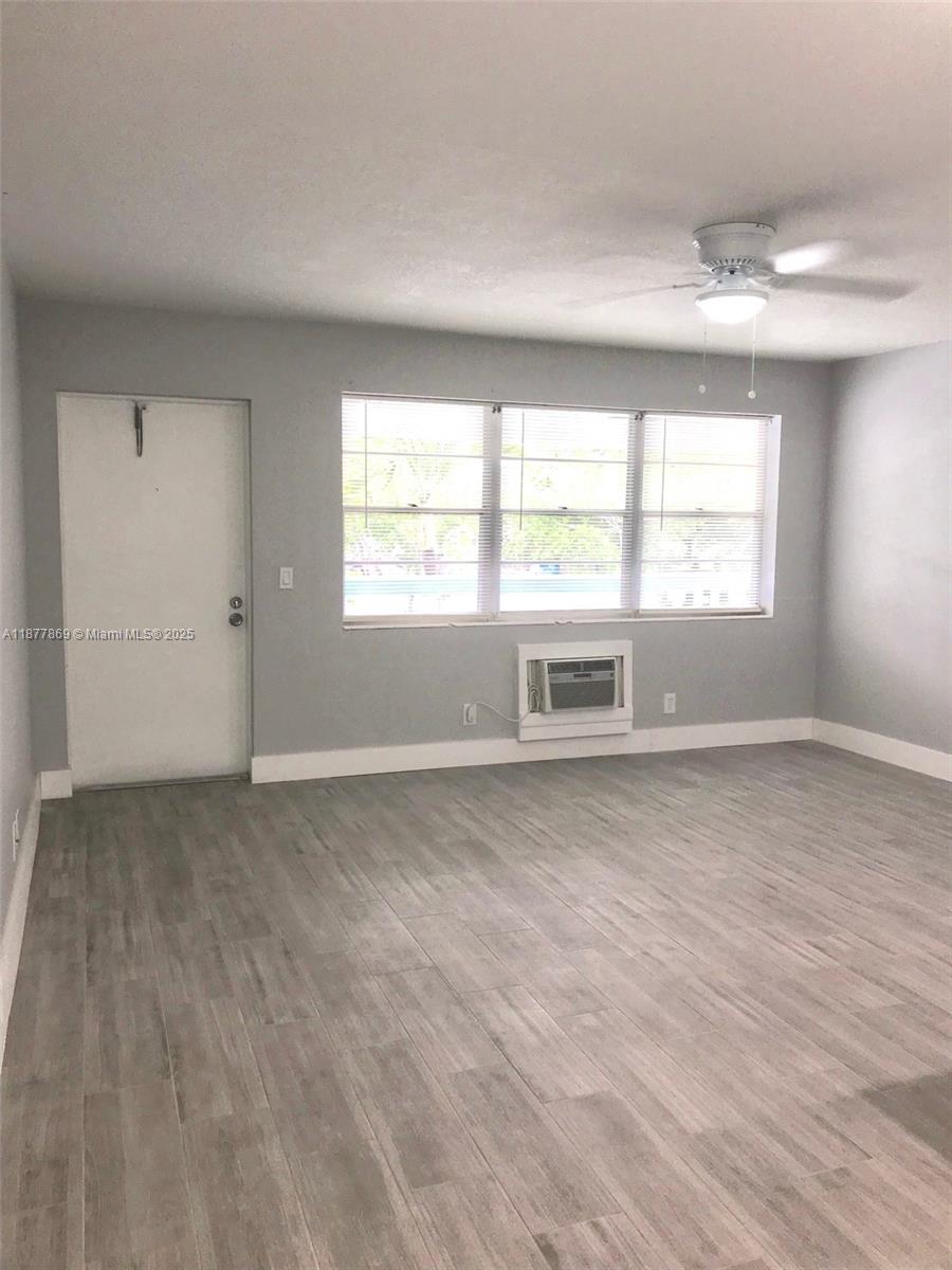 This room features gray walls, wood-look tile flooring, a ceiling fan, and a window air conditioner — 17 Keswick A # 17, Deerfield Beach FL 33442, DEERFIELD BEACH, FL