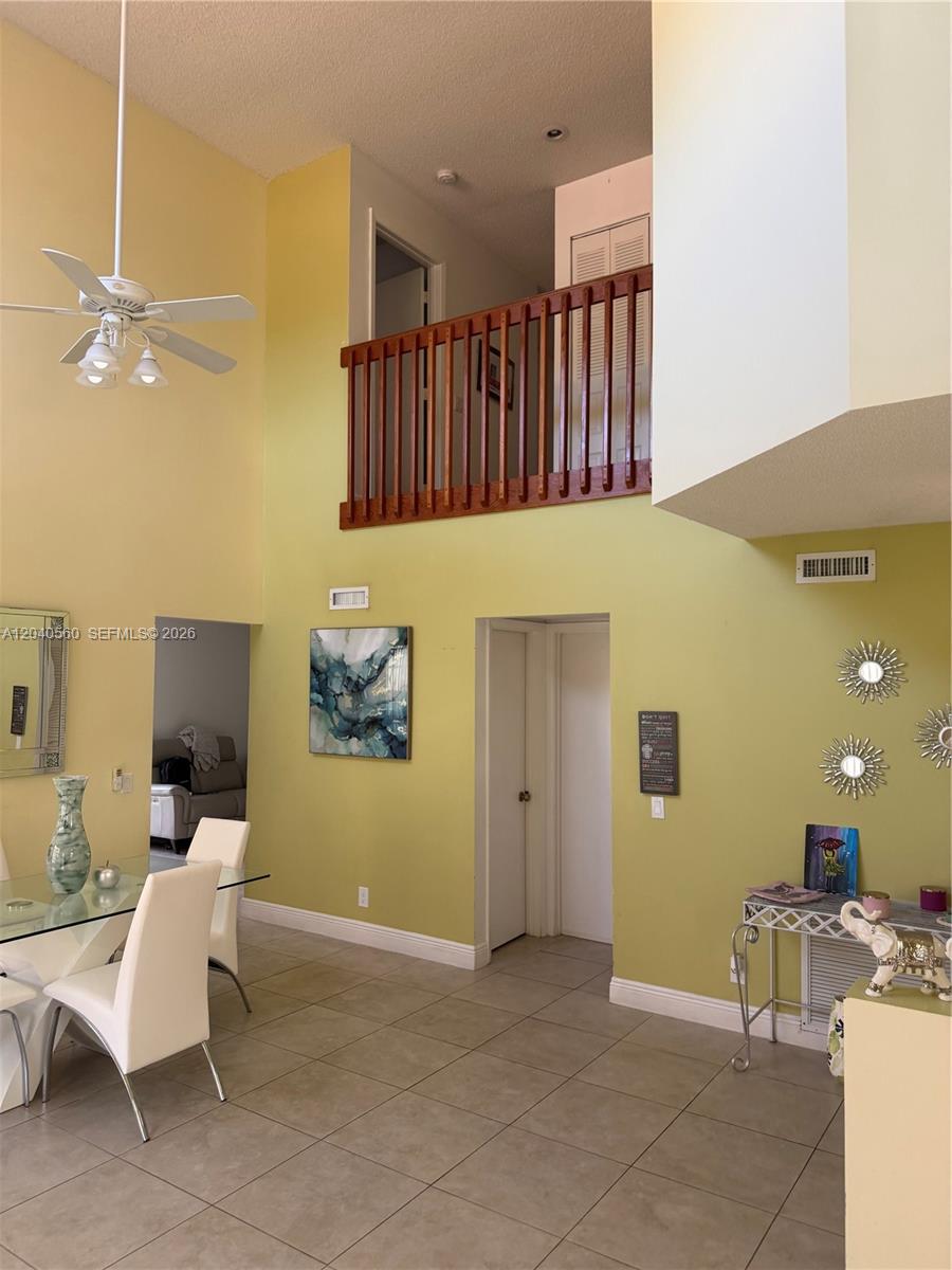 A dining area features a high ceiling, tile flooring, and a wooden balcony overlooking it — 1335 Seagrape Cir, Weston FL 33326, WESTON, FL
