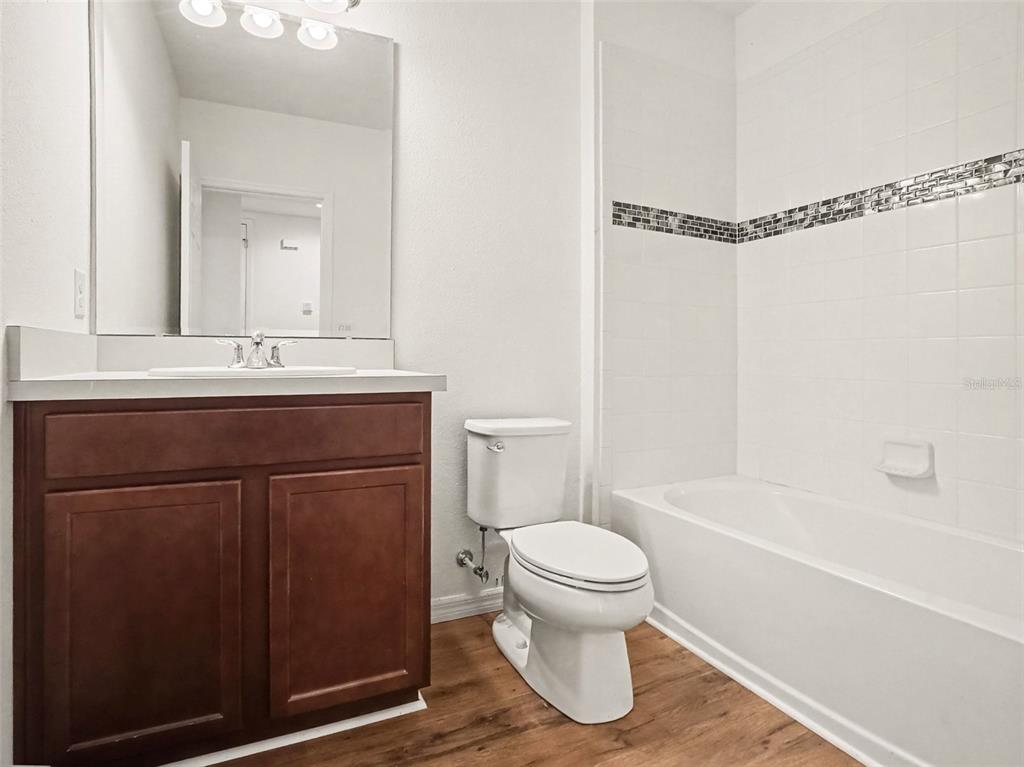 A bathroom features a dark wood vanity, a white toilet, and a tiled shower-tub combination — 5583 SABAL DRIVE, ST CLOUD, FL