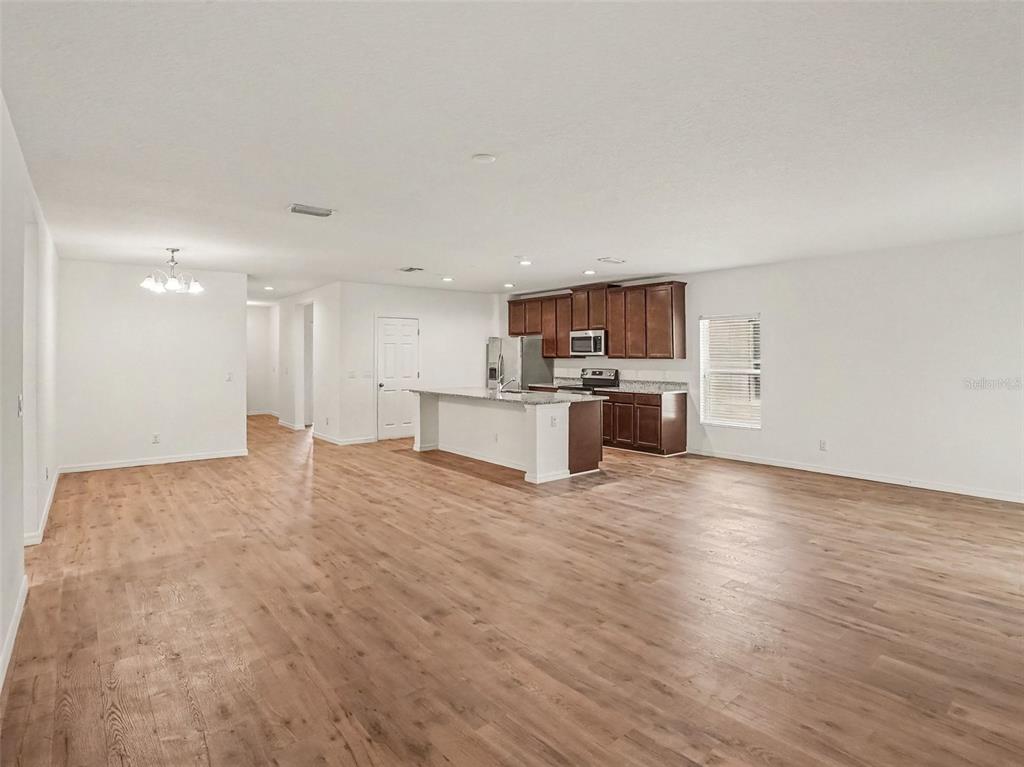 An open-concept kitchen and living area with wood-look flooring and dark wood cabinets — 5583 SABAL DRIVE, ST CLOUD, FL