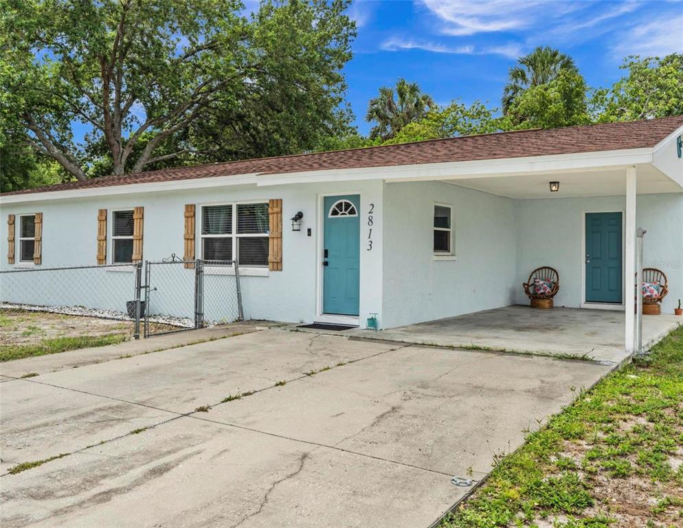 A light blue single-story house features a concrete driveway, a carport, and a teal door — 2813 DURHAM, TAMPA, FL