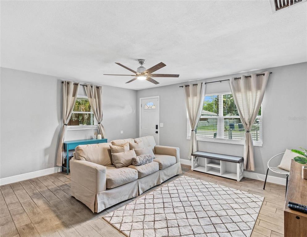 A living room with light gray walls, wood-look tile flooring, a sofa, and a ceiling fan — 2813 DURHAM, TAMPA, FL