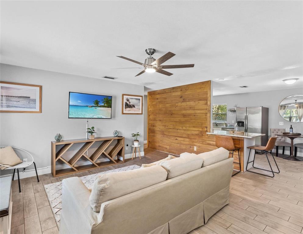 A living room with a wood-paneled accent wall opens into a kitchen with bar seating — 2813 DURHAM, TAMPA, FL