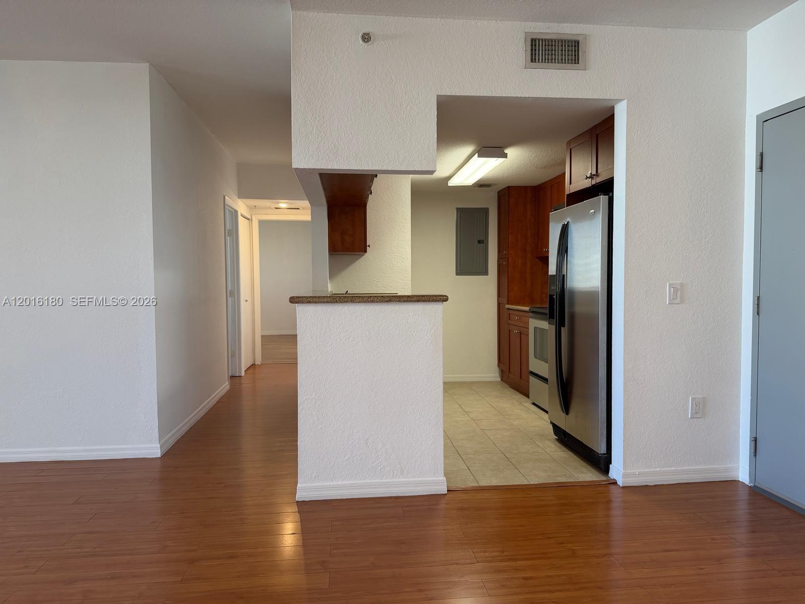 A kitchen with wood cabinets and stainless steel appliances opens to a living area — 36 NW 6th Ave # 1108, Miami FL 33128, MIAMI, FL