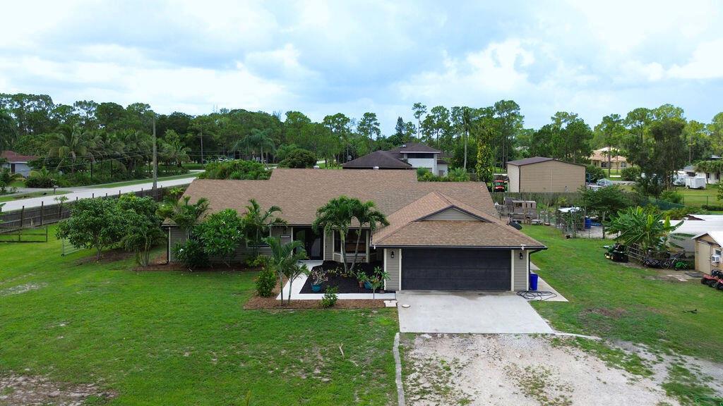 An aerial view of a single-story house with a brown shingled roof and attached garage — 14502 69th Street N, FL 33470, FL