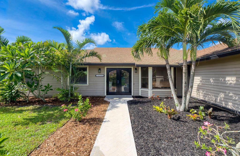 A single-story house exterior features a paved walkway leading to double glass front doors — 14502 69th Street N, FL 33470, FL