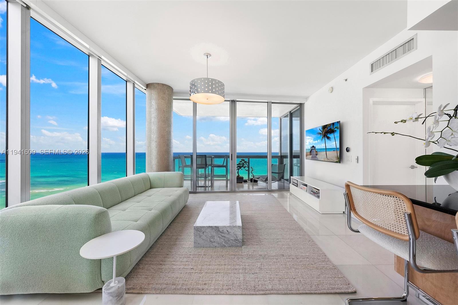 A modern living room features a light green sofa, marble coffee table, and ocean views — 6899 Collins Ave # 1205, Miami Beach FL 33141, MIAMI BEACH, FL