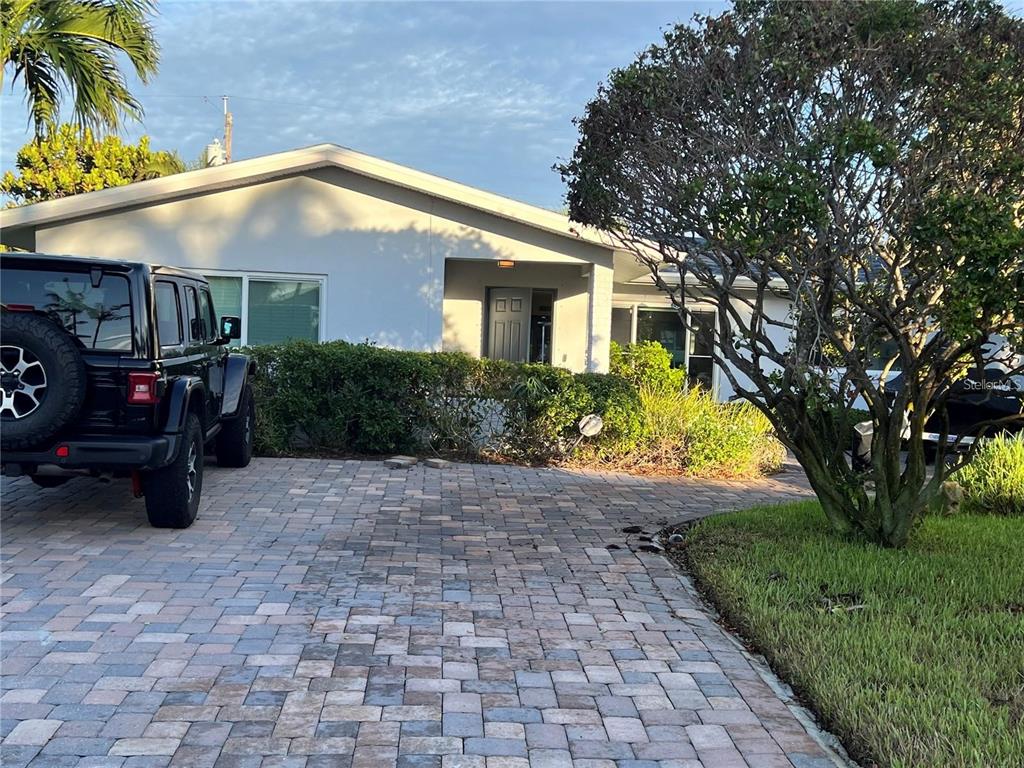 A paved driveway leads to the front entrance of a single-story house with landscaping — 2460 E VINA DEL MAR BOULEVARD, ST PETE BEACH, FL