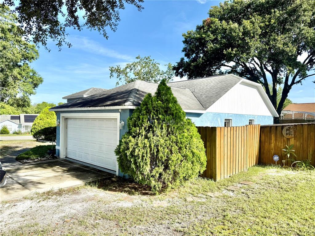 A blue house with a white garage door and a wooden fence in the yard — 3244 FIELDCREST TERRACE, DELTONA, FL