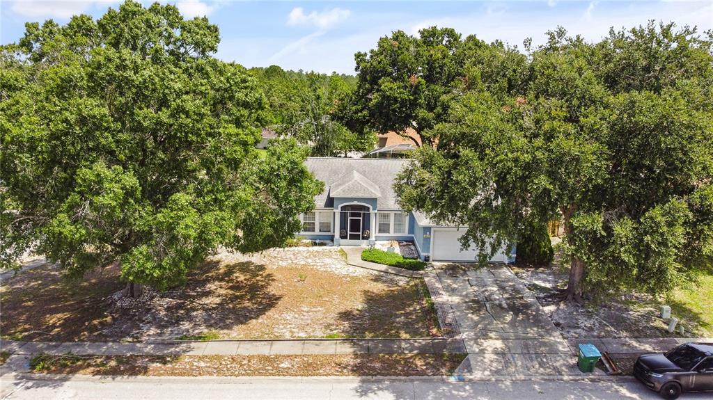 An aerial view of a single-story house with a driveway, front yard, and large trees — 3244 FIELDCREST TERRACE, DELTONA, FL