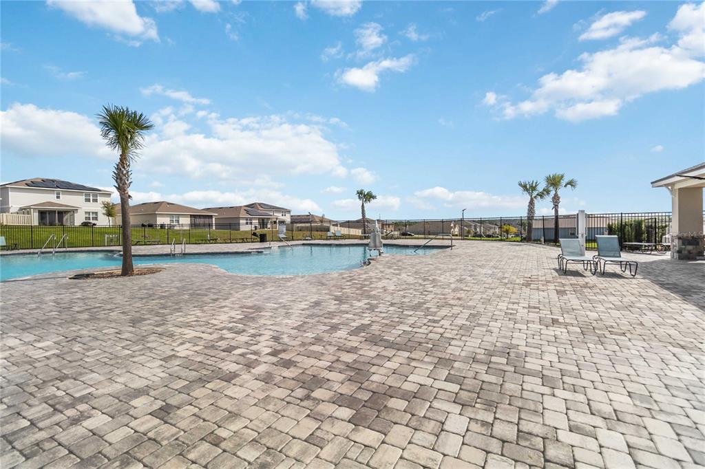 A community swimming pool with a paved deck, palm trees, and surrounding houses — 2620 MAGNOLIA AVENUE, DAVENPORT, FL