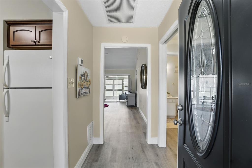 An entryway leads to a living area with light wood-look flooring and a glass door — 1136 VILLA LANE UNIT 96, APOPKA, FL