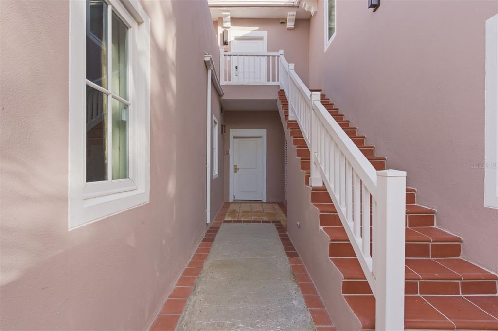 An outdoor walkway leads to a white door with a staircase on the right — Las Casitas I 1000 AVENUE EL CONQUISTADOR UNIT 5113-14-15, FAJARDO, PR