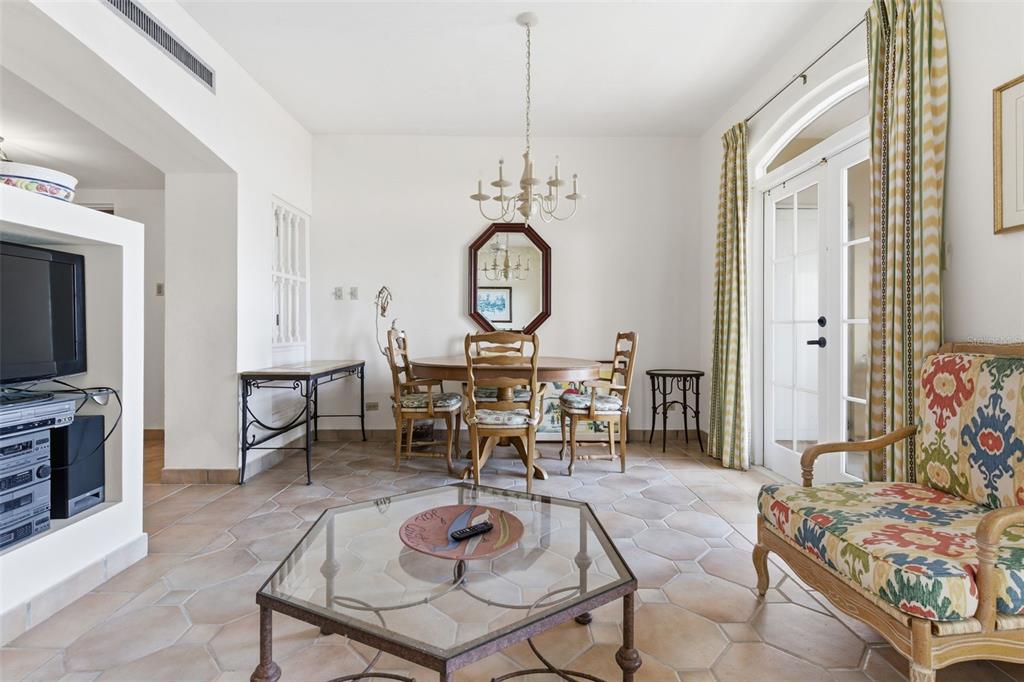 A dining area with a glass-topped table, chandelier, and tile flooring opens to a patio — Las Casitas I 1000 AVENUE EL CONQUISTADOR UNIT 5113-14-15, FAJARDO, PR