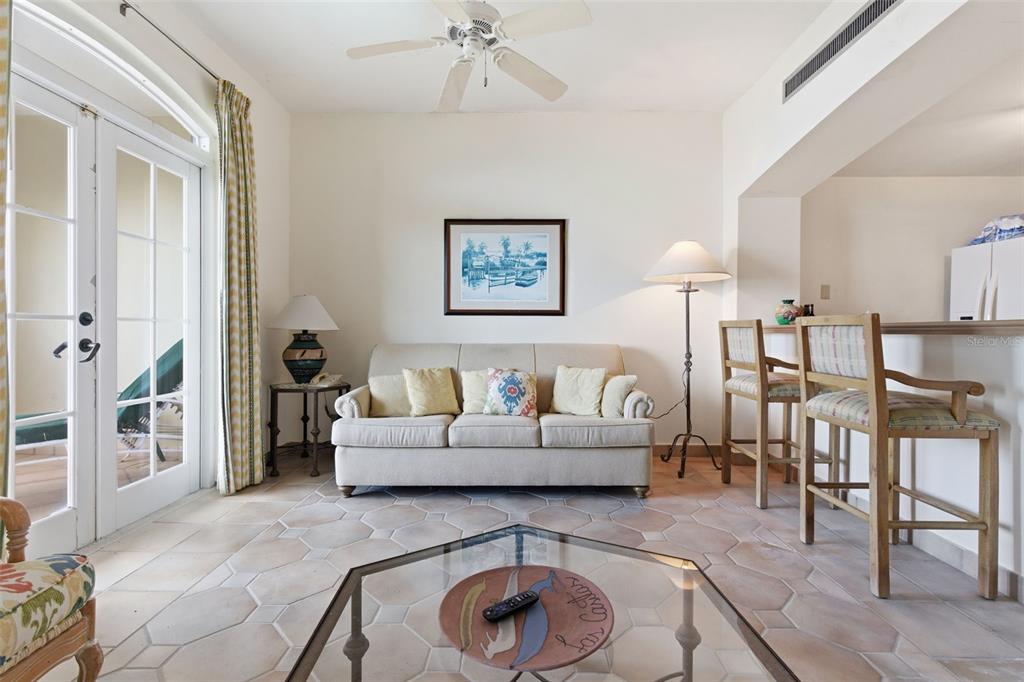 A living room features a beige sofa, tile flooring, a ceiling fan, and a breakfast bar — Las Casitas I 1000 AVENUE EL CONQUISTADOR UNIT 5113-14-15, FAJARDO, PR