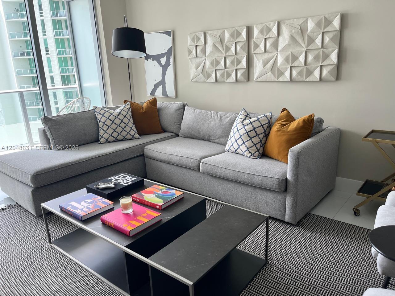 A living room features a grey sectional sofa, a black coffee table, and wall art — 1300 Brickell Bay Dr # 2208, Miami FL 33131, MIAMI, FL