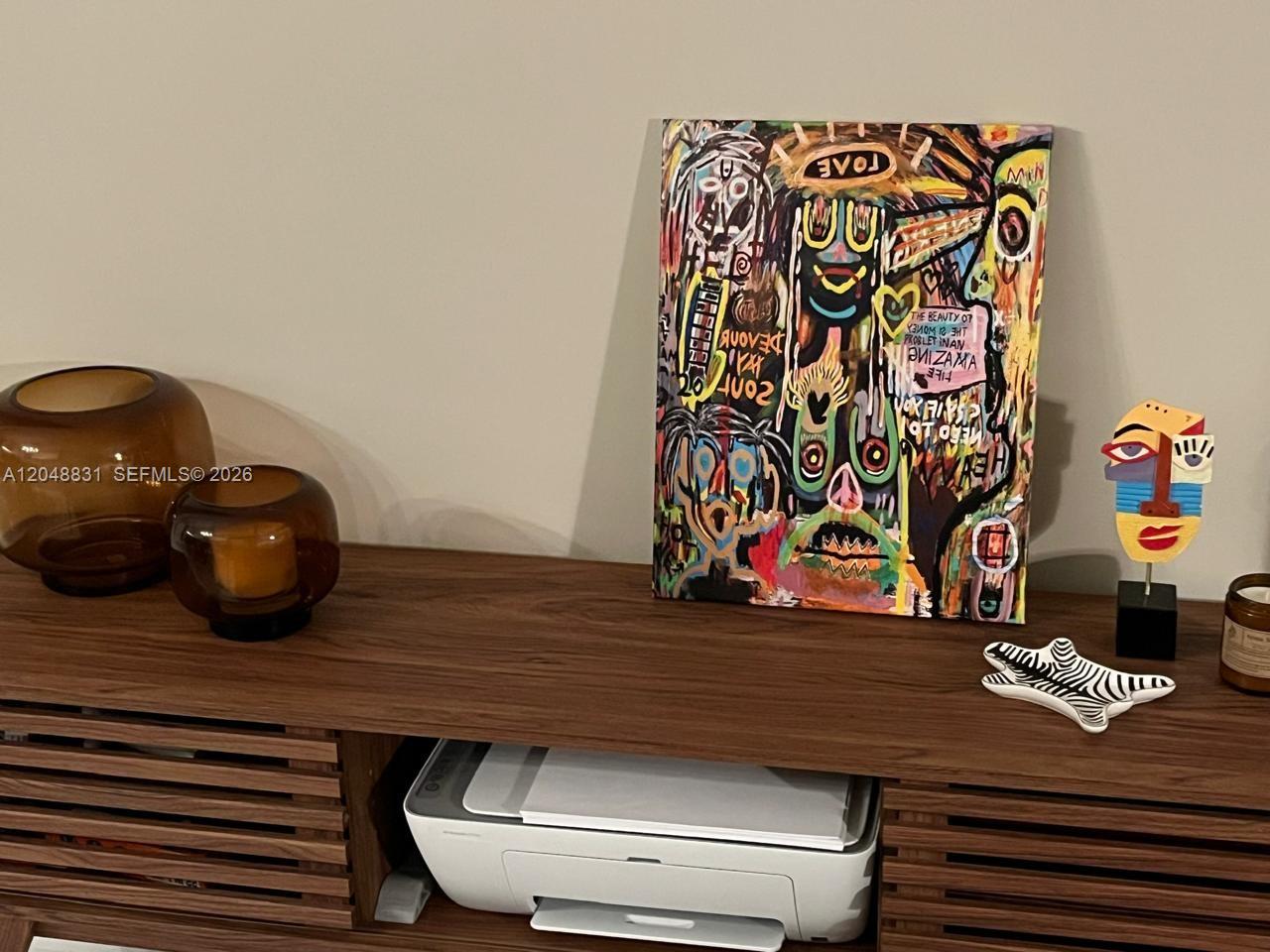 A wooden console table holds a colorful abstract painting, a printer, and decorative home accessories — 1300 Brickell Bay Dr # 2208, Miami FL 33131, MIAMI, FL