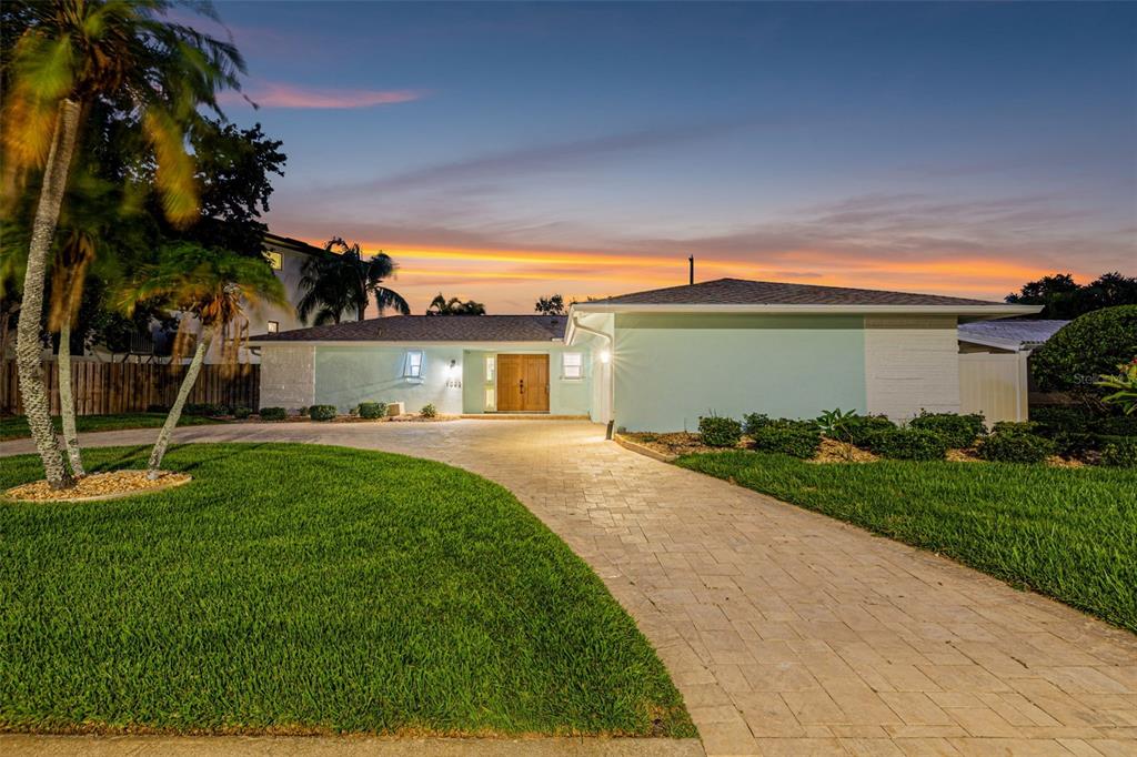 A single-story house with a light blue exterior and a paved driveway at sunset — 1022 EDEN ISLE DRIVE NE, ST PETERSBURG, FL