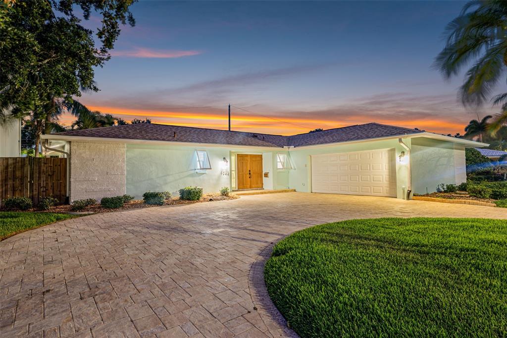 A single-story house with a light green exterior, a paved driveway, and a two-car garage — 1022 EDEN ISLE DRIVE NE, ST PETERSBURG, FL