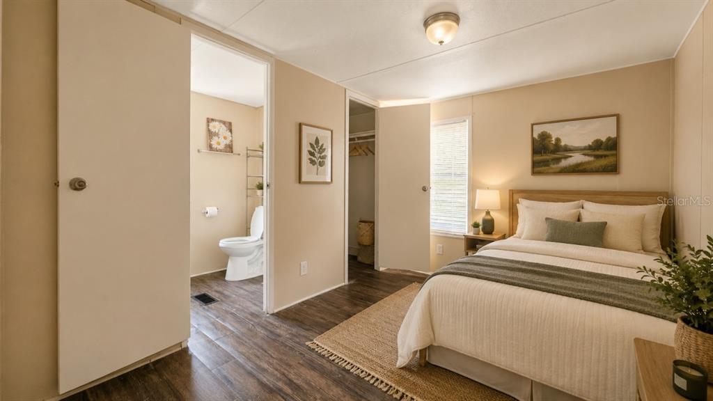 A bedroom with a bed, a bathroom doorway, a closet, and wood-look flooring — 24325 SW 46TH AVENUE, NEWBERRY, FL