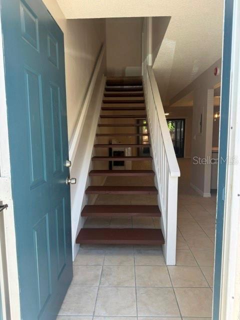 An open door reveals a staircase with dark wood treads and white railings in a foyer — 3960 WILLOW TRAIL RUN UNIT 1401, PORT ORANGE, FL