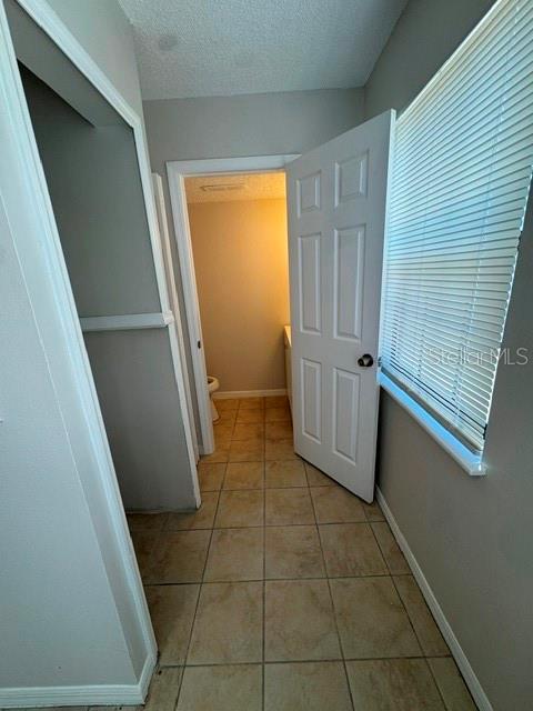 A tiled hallway leads to a bathroom doorway with a white door and window blinds — 3960 WILLOW TRAIL RUN UNIT 1401, PORT ORANGE, FL