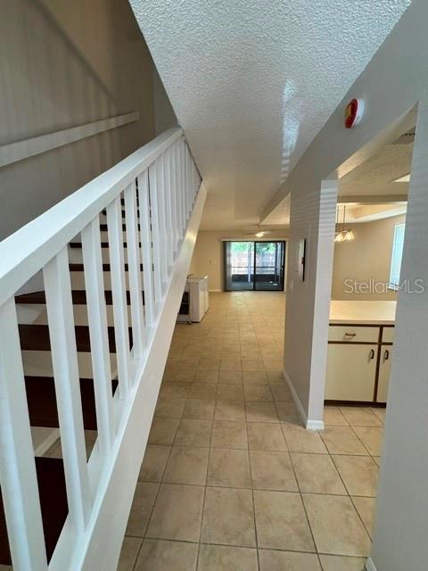 A staircase with white railings leads to a tiled hallway with a view of a patio — 3960 WILLOW TRAIL RUN UNIT 1401, PORT ORANGE, FL
