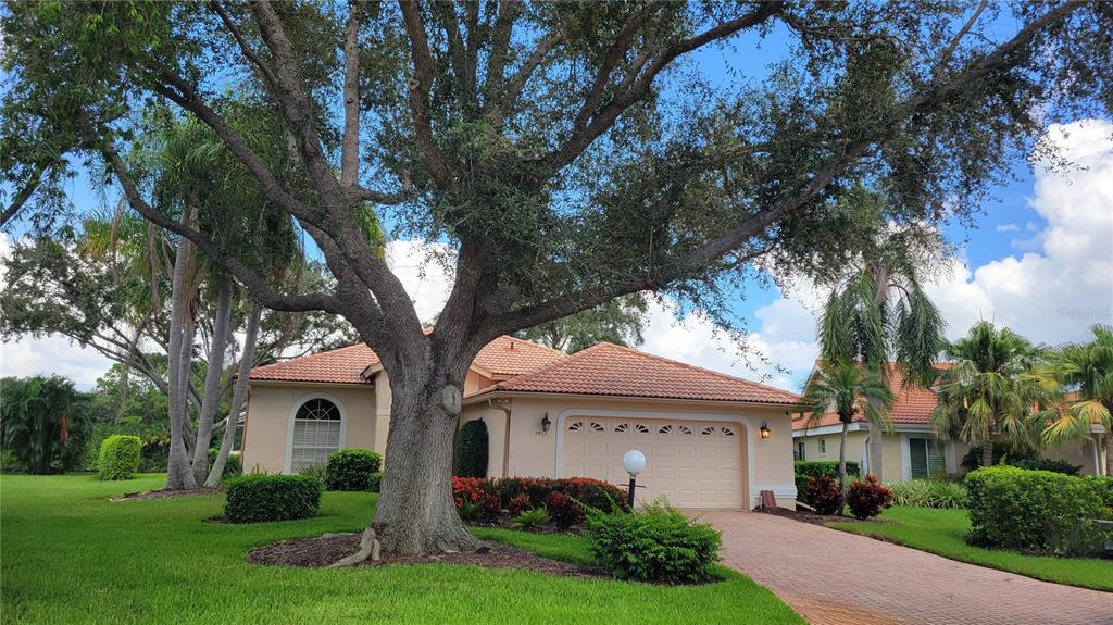 A single-story house with a tile roof and a large oak tree in the yard — 7557 FAIRLINKS COURT, SARASOTA, FL