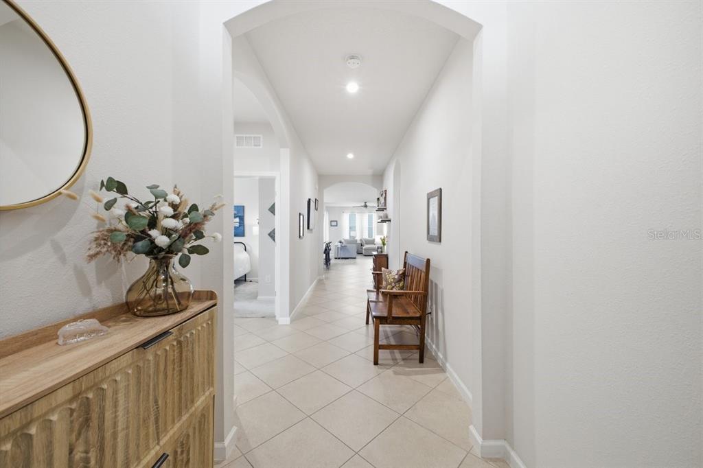 A tiled hallway features an arched entryway, a wooden bench, and a console table — 5907 114TH AVENUE E, PARRISH, FL