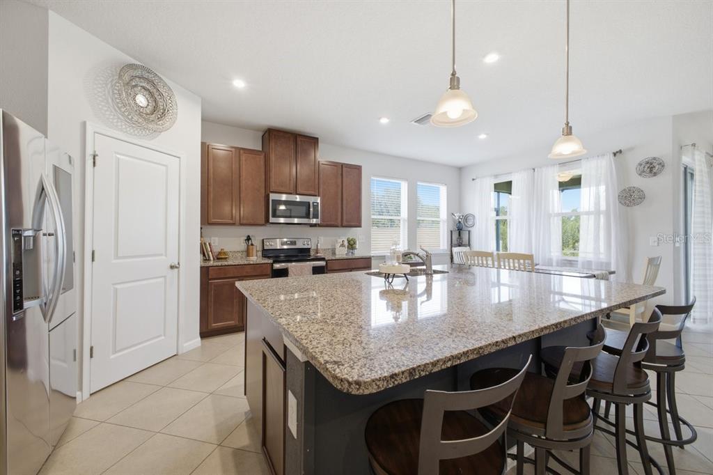 A kitchen with a large granite island, dark wood cabinets, and stainless steel appliances — 5907 114TH AVENUE E, PARRISH, FL