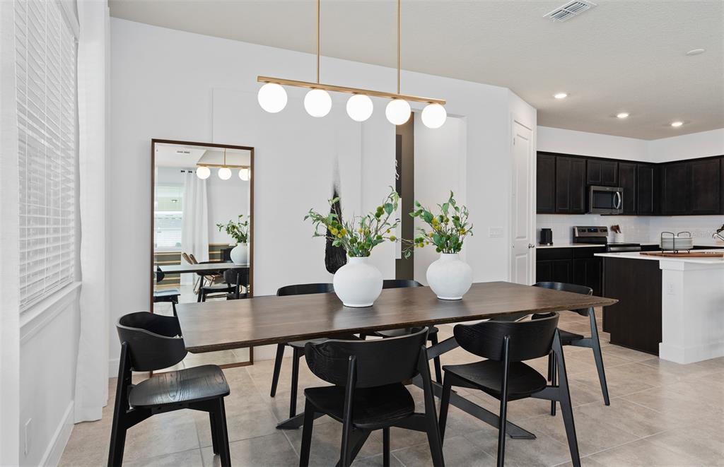 A dining room features a dark wood table, black chairs, and a modern linear light fixture — 4747 HARRINGTON FIELDS DRIVE, DAVENPORT, FL