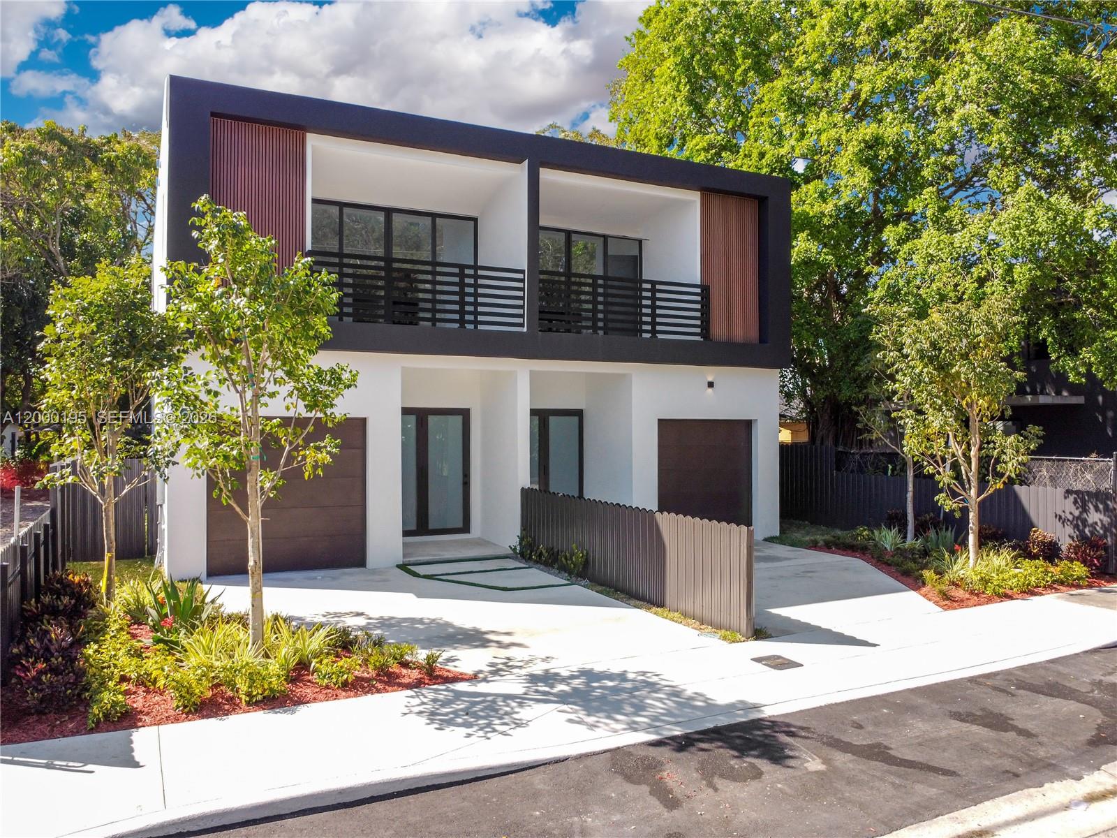 A modern two-story duplex features white stucco walls, dark wood accents, and a black balcony — 5116 NW 3rd Ave # 1, Miami FL 33127, MIAMI, FL