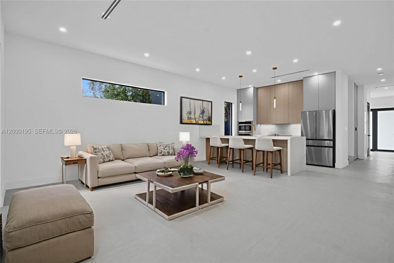 A modern open-concept living room features a beige sofa, a coffee table, and a kitchen — 5116 NW 3rd Ave # 1, Miami FL 33127, MIAMI, FL