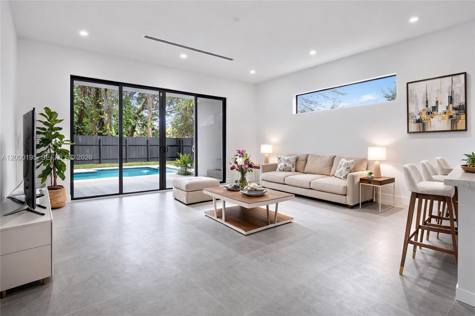 A modern living room features tile floors, a beige sofa, and sliding doors to a pool — 5116 NW 3rd Ave # 1, Miami FL 33127, MIAMI, FL