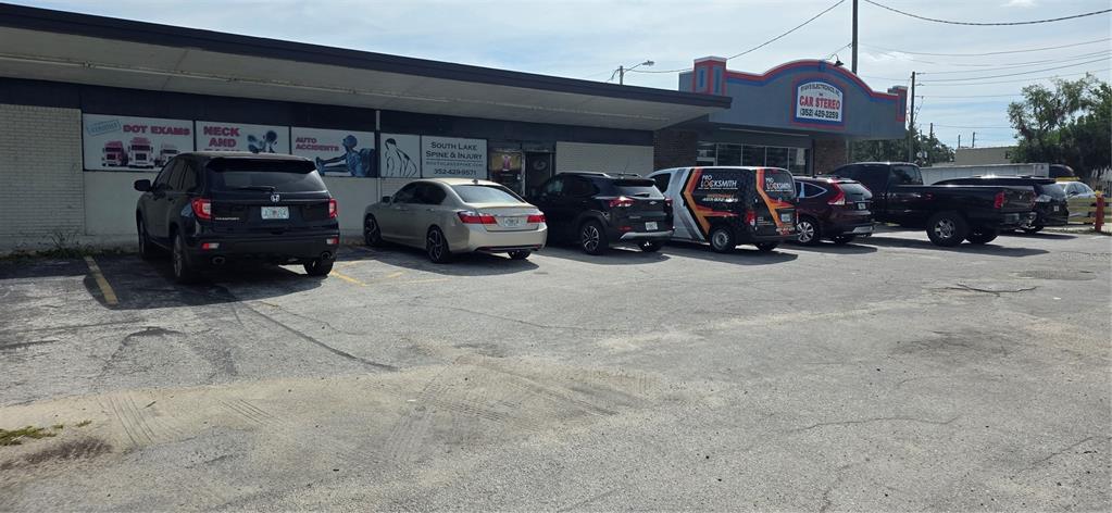 A commercial building exterior features a parking lot with several parked vehicles — 237 W BROAD STREET, GROVELAND, FL