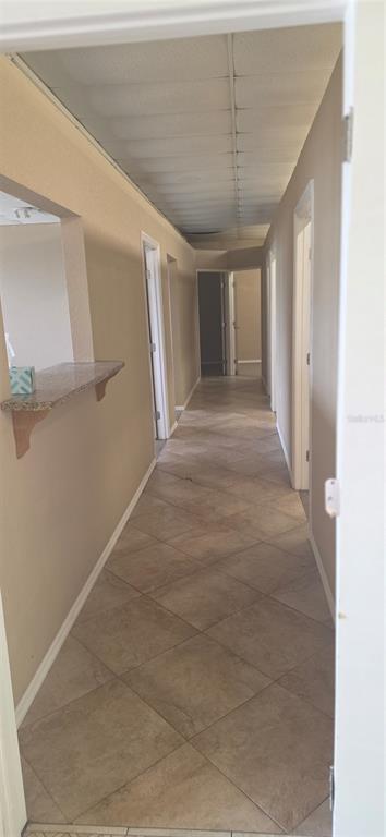 A long hallway with beige tile flooring leads to several closed doors under a drop ceiling — 237 W BROAD STREET, GROVELAND, FL