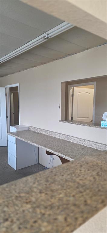 A room features a long granite-topped desk with white drawers and a pass-through window — 237 W BROAD STREET, GROVELAND, FL