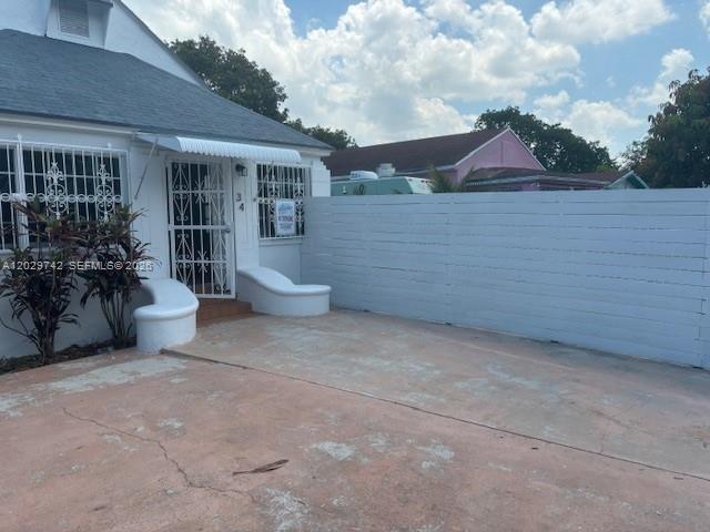 A white house with a metal security door and a long horizontal privacy fence — 34 NW 69th St, Miami FL 33150, MIAMI, FL