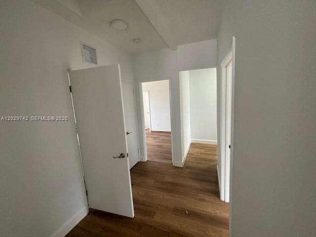 A hallway with white walls, wood-look flooring, and several closed and open doorways — 34 NW 69th St, Miami FL 33150, MIAMI, FL